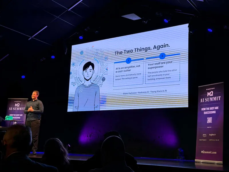 Blake Harkness presenting on stage at the M2 AI Summit in Christchurch, with a slide reading The Two Things, Again